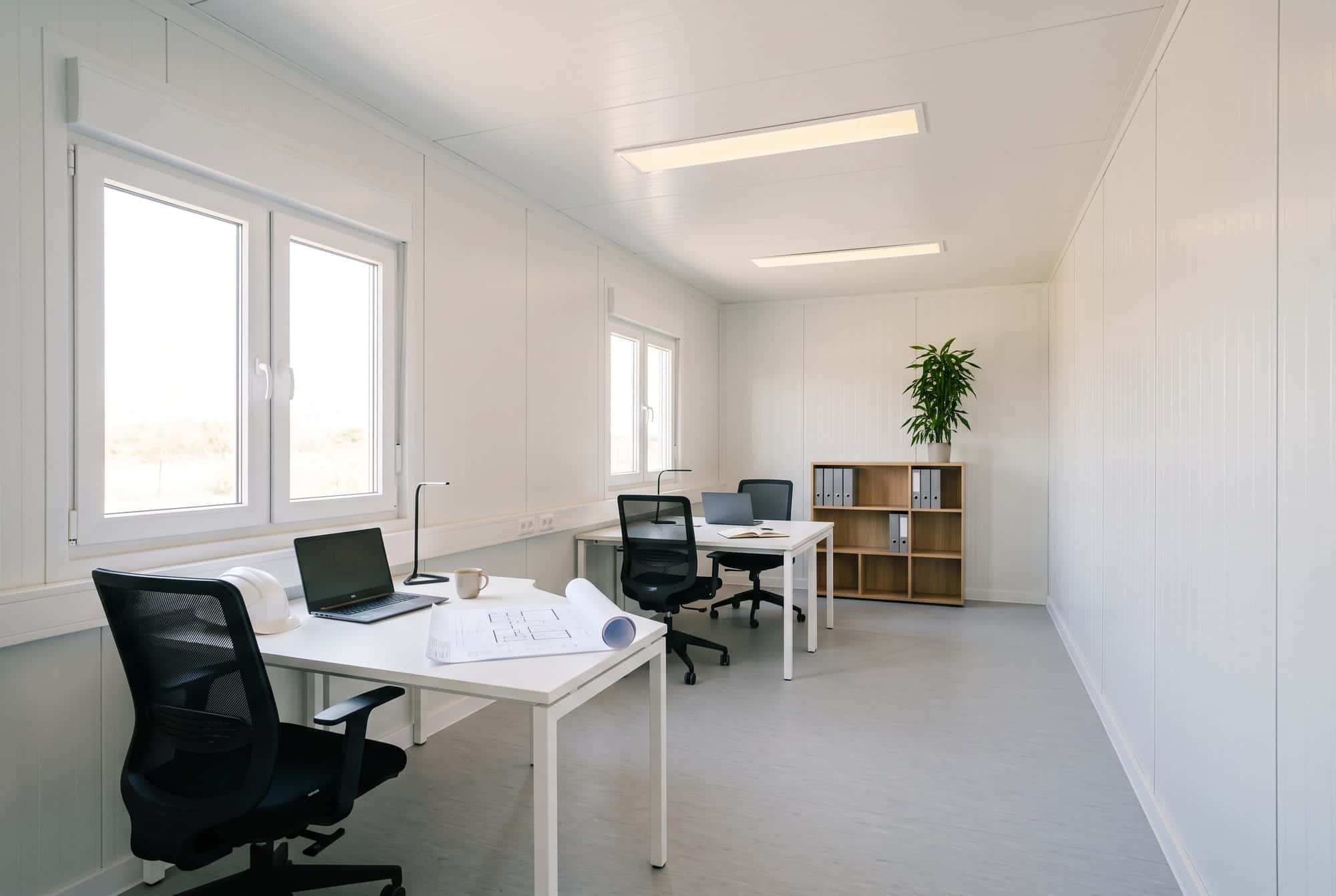 Interior de un módulo preparado como oficina, con dos puestos de trabajo junto a las ventanas.
